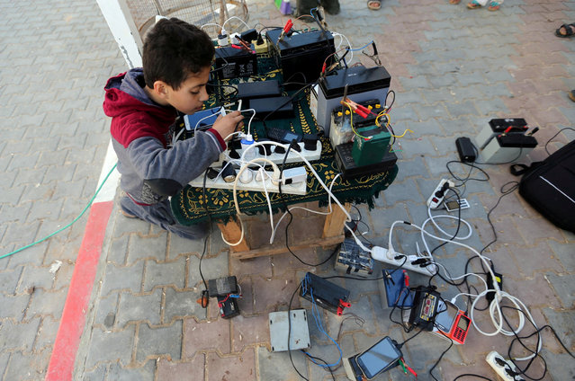 A Palestinian boy charges a mobile phone from batteries offered as a free service in his neighborhood which experiences power shortages, in Johr El-Deek in Gaza January 31, 2018. (Photo by Ibraheem Abu Mustafa/Reuters)