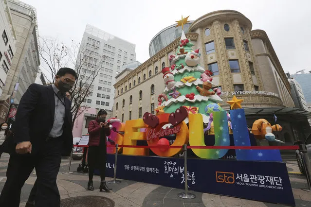 People wearing face masks to help protect against the spread of the coronavirus walk past a Christmas tree set up for a year-end festival featuring a lantern at a shopping street in Seoul, South Korea, Friday, November 20, 2020. South Korea's prime minister has urged the public to avoid social gatherings and stay at home as much as possible as the country registered more than 300 new virus cases for a third consecutive day. (Photo by Ahn Young-joon/AP Photo)