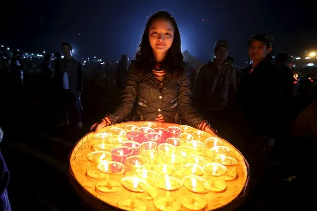 A girl carries candles for lighting traditional home-made paper lanterns during the annual Tazaungdaing balloon festival in Taunggyi, Myanmar November 19, 2015. (Photo by Soe Zeya Tun/Reuters)