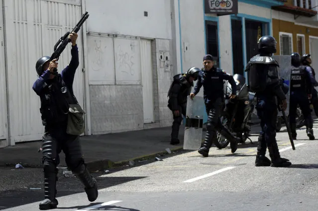 A riot police officer fires into the air during clashes with opposition supporters in a rally to demand a referendum to remove President Nicolas Maduro in San Cristobal, Venezuela October 24, 2016. (Photo by Carlos Eduardo Ramirez/Reuters)