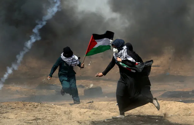 Female demonstrators run for cover from tear gas fired by Israeli forces during a protest where Palestinians demand the right to return to their homeland, at the Israel-Gaza border in the southern Gaza Strip, May 11, 2018. (Photo by Ibraheem Abu Mustafa/Reuters)