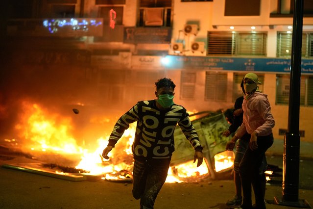A person runs past a torched police vehicle as youth led protests calling for healthcare and education reforms turned violent, in Sale, Morocco, Wednesday, October 1, 2025. (Photo by Mosa'ab Elshamy/AP Photo)