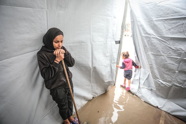 Palestinians, whose homes were destroyed during Israel's two-year attacks, have hard times trying to evacuate the water after their makeshift tents were flooded with the intense rain at Al Yarmouk Camp in Gaza City, Gaza on November 14, 2025. The onset of cold weather and rainfall has made living conditions even more difficult for residents living in makeshift tents. (Photo by Hamza Z. H. Qraiqea/Anadolu via Getty Images)