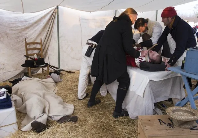 Albert Roberts (2nd right) of Nashville, Tennessee plays a doctor attempting to save an injured American fighter, Mark Miller of West Monroe, Louisiana, following a reenactment of the Battle of New Orleans in the War of 1812, marking its bicentennial in Chalmette, Louisiana January 10, 2015. (Photo by Lee Celano/Reuters)