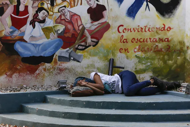 In this May 8, 2018 photo, a student rests in a courtyard at the Nacional University below a mural depicting national hero Augusto Sandino and the Spanish message: “Turning darkness into clarity” in Managua, Nicaragua. Anti-government protest leaders are struggling to wrangle the diverse viewpoints of students from multiple universities into one coherent voice. (Photo by Alfredo Zuniga/AP Photo)