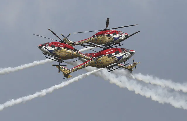 Sarang, a helicopter display team of Indian Air Force, perform aerobatic maneuvers on the inaugural day of Aero India 2021 at Yelahanka air base in Bengaluru, India, Wednesday, February 3, 2021. Aero India is a biennial event with flying demonstrations by stunt teams and militaries and commercial pavilions where aviation companies display their products and technology. (Photo by Aijaz Rahi/AP Photo)