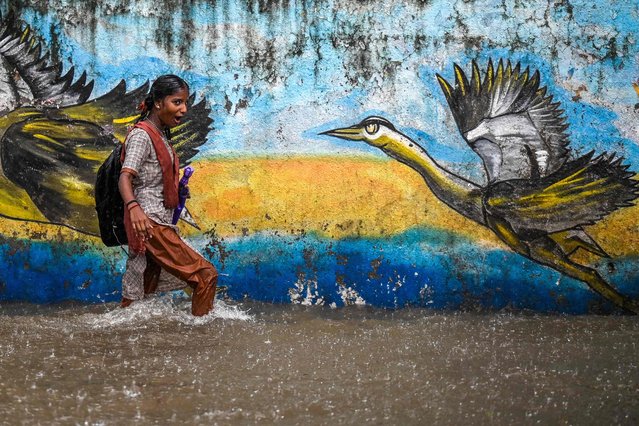 A schoolgirl reacts as she wades through a flooded street during heavy rain showers in Mumbai on August 18, 2025. (Photo by Punit Paranjpe/AFP Photo)