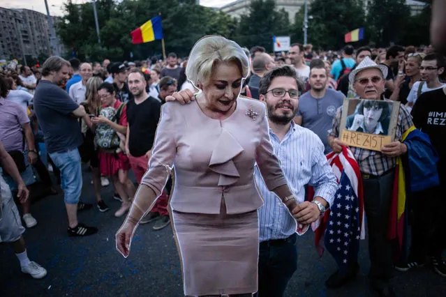 A demonstrator holds a full- size cardboard cut- out depicting Romania' s Prime Minister Viorica Dancila during a gathering in front of the Romanian Prime Minister' s office building on June 21, 2018 in Bucharest, Romania. Around 5,000 people gathered to celebrate the conviction of Liviu Dragnea, leader of the ruling left- wing social democrat party (PSD) and president of the Deputy Chamber, to three- and- a-half years in prison over a fake jobs scandal. (Photo by Adrian Catu/AFP Photo)