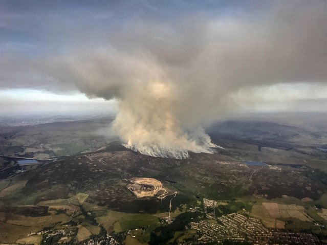 These dramatic pictures taken on Monday evening show the fire on Saddleworth Moor in Stalybridge, England taking hold and sending huge plumes into the sky on June 27, 2018. A major incident has been declared after a huge moorland fire forced dozens of residents to flee their homes in Greater Manchester. The army is on standby to help tackle the blaze which has been raging for several days on Saddleworth Moor. Some 34 properties have been evacuated in Carrbrook, Stalybridge, while police have confirmed some nearby schools will be closed. Public Health England has urged residents to keep windows and doors shut as smoke and flames could be seen for miles. (Photo by Kate MacRae/South West News Service)