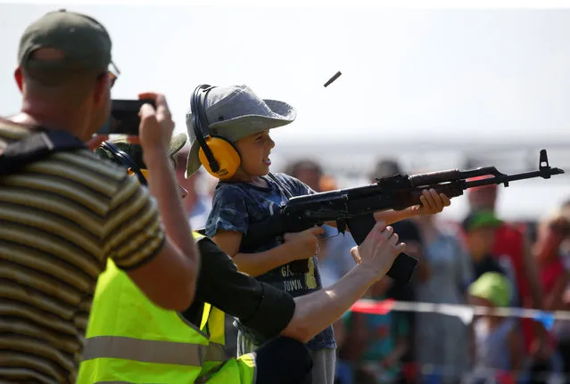 An instructor teaches a boy to shoot a Kalashnikov automatic rifle during the International Army Games 2018, in Alabino, outside Moscow, Russia on July 28, 2018. (Photo by Sergei Karpukhin/Reuters)