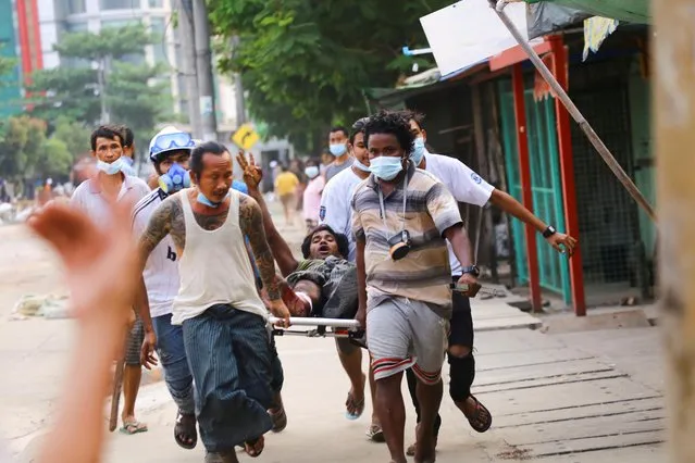 A man who was shot during a crackdown on anti-coup protesters shows a three-finger salute as he is helped in Thingangyun, Yangon, Myanmar on March 14, 2021. (Photo by Reuters/Stringer)