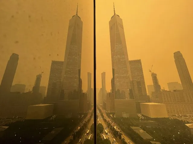 Traffic moves along West Street past One World Trade Center, in this mirror image reflected in the facade of a building, Wednesday, June 7, 2023, in New York, amidst smokey haze from wildfires in Canada. Smoke from Canadian wildfires poured into the U.S. East Coast and Midwest on Wednesday, covering the capitals of both nations in an unhealthy haze, holding up flights at major airports and prompting people to fish out pandemic-era face masks. (Photo by Andy Bao/AP Photo)