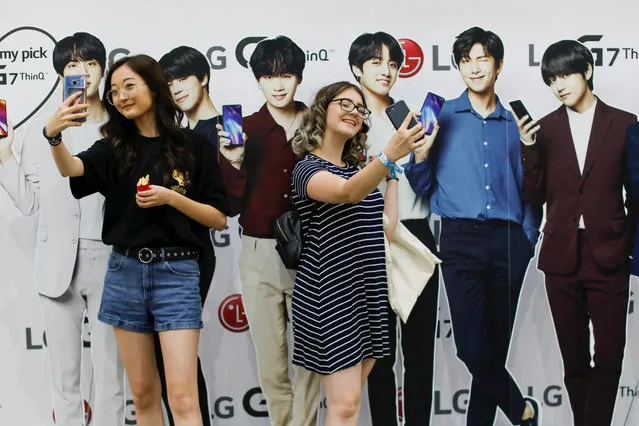 Attendees take selfies with cardboard cutout figures at KCON USA, billed as the world's largest Korean culture convention and music festival in Los Angeles, California on August 11, 2018. In June, the boy band BTS became the first K-pop group to top the Billboard 200 album chart, with “Love Yourself: Tear”. “We K-pop artists are really proud of them, because we know how hard it is to make it in the industry”, Ailee, a U.S.-born K-pop star whose given name is Yejin Lee, said in a phone interview. “The fact that they opened up those doors and cleared the way for us, it's a huge hope for us”, said Ailee, who performed at KCON. (Photo by Mike Blake/Reuters)