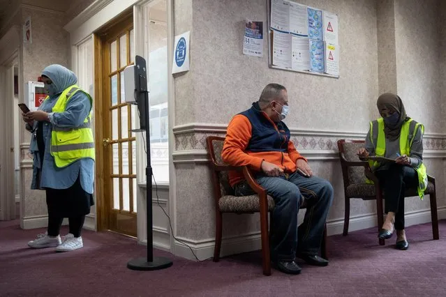 A volunteer assists a man to fill out paperwork before he is vaccinated against the coronavirus at a clinic hosted by the Arab Community Center for Economic and Social Services (ACCESS) in Sterling Heights, Michigan, April 20, 2021. (Photo by Emily Elconin/Reuters)