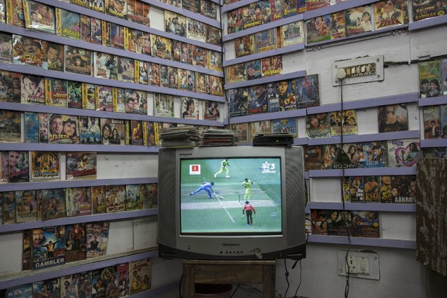 Indians at a shop that sells Bollywood films and music in New Delhi, India, watch on television their cricket team play Pakistan in the World Cup Pool B match at the Adelaide Oval, Sunday, February 15, 2015. (Photo by Tsering Topgyal/AP Photo)