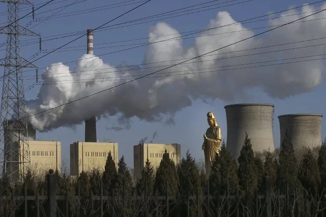 A Avalokitesvara Bodhisattva statue is seen next to chimneys of a power plant in Beijing, China, January 18, 2016. (Photo by Reuters/China Daily)