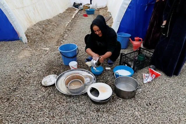 A displaced Iraqi woman, who fled the Islamic State stronghold of Mosul, washes dishes at Khazer camp, Iraq December 13, 2016. (Photo by Ammar Awad/Reuters)