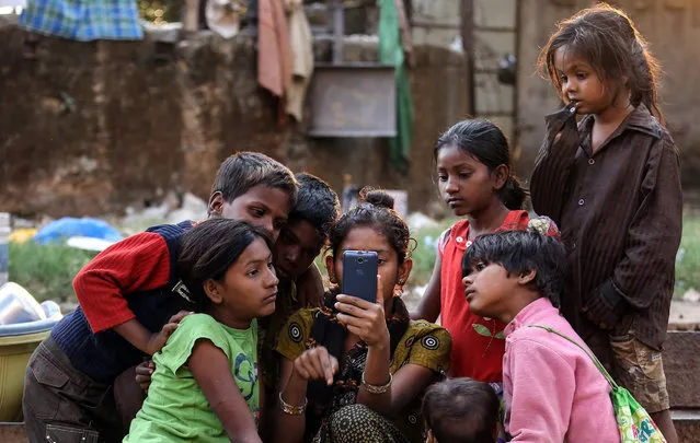 Indian homeless children watch movie in a cell phone on the roadside, in Mumbai, India, 20 January 2016. According to a recent report, the first-ever census of street children conducted by the Tata Institute of Social Sciences (TISS) and the voluntary organization Action Aid India suggest that more than 37,000 children live on the streets of the Indian metropole. (Photo by Divyakant Solanki/EPA)