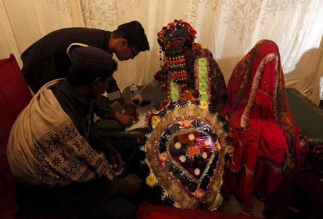 A groom signs marriage documents during a mass marriage ceremony in Karachi, Pakistan, January 24, 2016. (Photo by Akhtar Soomro/Reuters)