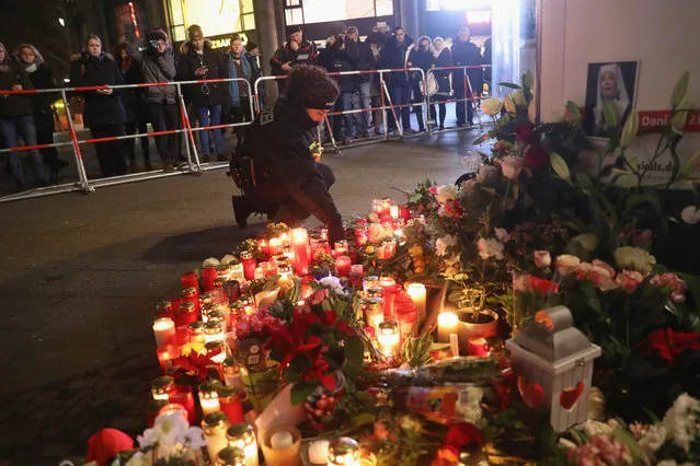 A policewoman places a candle on behalf of a mourner at a makeshift memorial the day after a truck drove into a crowded Christmas market in the city center on December 20, 2016 in Berlin, Germany. So far 12 people are confirmed dead and 45 injured. Authorities have confirmed they believe the incident was an attack and have arrested a Pakistani man who they believe was the driver of the truck and who had fled immediately after the attack. Among the dead are a Polish man who was found on the passenger seat of the truck. Police are investigating the possibility that the truck, which belongs to a Polish trucking company, was stolen yesterday morning. (Photo by Sean Gallup/Getty Images)