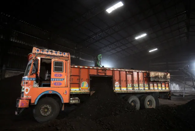 A worker shovels coal in a supply truck at a yard on the outskirts of Ahmedabad, India, October 25, 2018. (Photo by Amit Dave/Reuters)