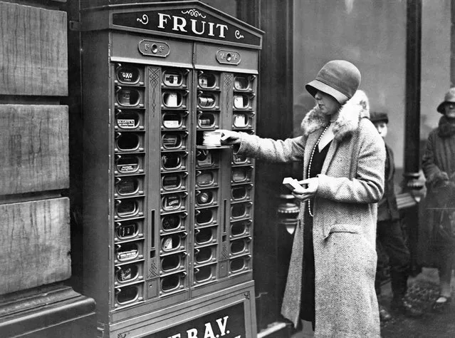 A vending machine enables a daytime worker to purchase goods after the shops have closed. London, England, ca. 1920. (Photo by Hulton-Deutsch/Hulton-Deutsch Collection/Corbis via Getty Images)