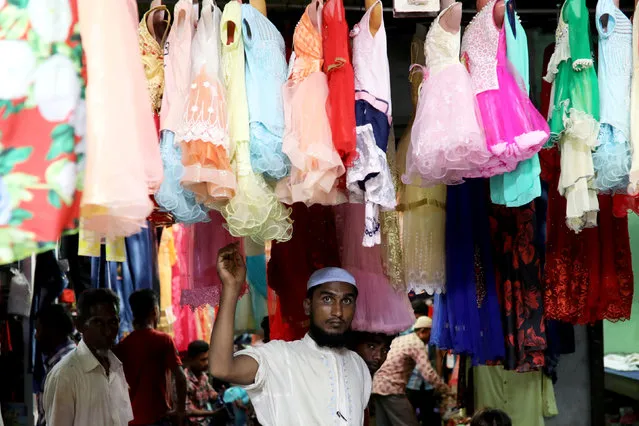 A Rohingya refugee checks children's dresses for sell ahead of Eid al-Adha in Kutupaloong Refugee camp in Cox's Bazar, Bangladesh on August 21, 2018. (Photo by Mohammad Ponir Hossain/Reuters)