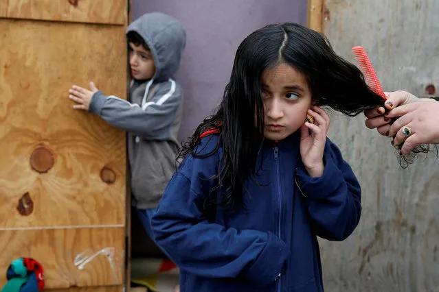 On the eve of International Migrants Day by United Nations, Lia, a Kurdish girl from Iraq, has her hair brushed by her mother at a camp for migrants in Grande Synthe, France December 17, 2016. (Photo by Pascal Rossignol/Reuters)