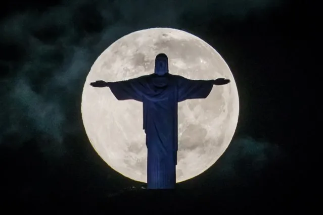 A full moon sets behind the Christ the Redeemer statue on top of Corcovado hill in Rio de Janeiro, Brazil, on May 25, 2013. (Photo by Yasuyoshi Chiba/AFP Photo)