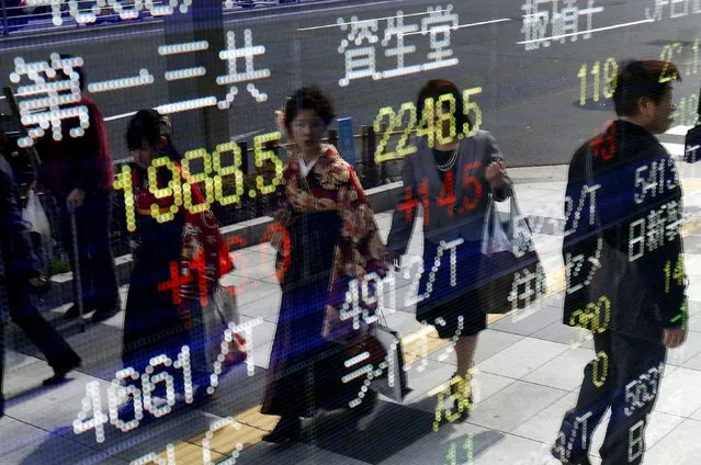 Women wearing Hakama, or Japanese traditional Kimono, are reflected in an electronic board, showing various stock prices, outside a brokerage in Tokyo, March 23, 2015. (Photo by Yuya Shino/Reuters)