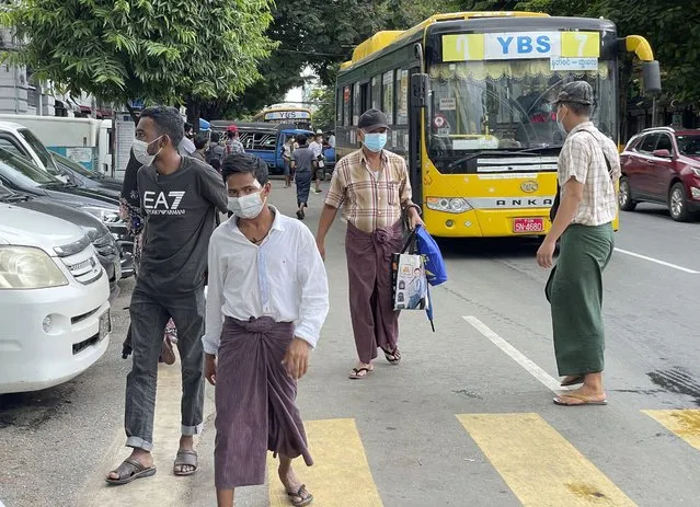 Commuters wearing face masks walk on a street after getting off a bus in Yangon, Myanmar, Thursday, July 8, 2021. Myanmar is facing a a rapid rise in COVID-19 patients and a shortage of oxygen supplies just as the country is consumed by a bitter and violent political struggle since the military seized power in February. (Photo by AP Photo/Stringer)