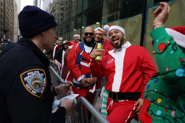 A police officer writes a ticket for a reveller at the SantaCon in New York City, New York, U.S., December 9, 2023. (Photo by David Dee Delgado/Reuters)