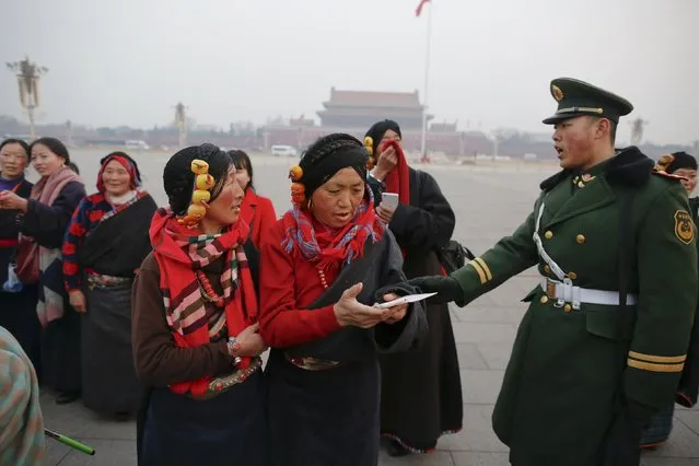 A paramilitary policeman tells women wearing traditional clothes to leave Tiananmen Square shortly after a flag-raising ceremony as the area near the Great Hall of the People is prepared for upcoming annual sessions of the National People's Congress (NPC) and Chinese People's Political Consultative Conference (CPPCC) in Beijing March 3, 2016. (Photo by Damir Sagolj/Reuters)