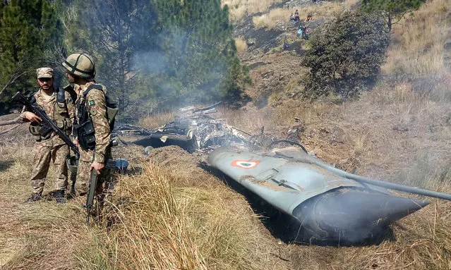 Pakistani soldiers stand next to what Pakistan says is the wreckage of an Indian fighter jet shot down in Pakistan controled Kashmir at Somani area in Bhimbar district near the Line of Control on February 27, 2019. Pakistan said on February 27 it shot down two Indian warplanes in its airspace over disputed Kashmir, in a dramatic escalation of a confrontation that has ignited fears of an all-out conflict between the nuclear-armed neighbours. (Photo by AFP Photo/Stringer)