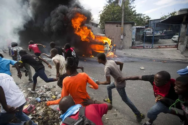 Demonstrators run away from police who are shooting in their direction, as a car burns during a protest demanding the resignation of Haitian President Jovenel Moise in Port-au-Prince, Haiti, Tuesday, February 12, 2019. (Photo by Dieu Nalio Chery/AP Photo)