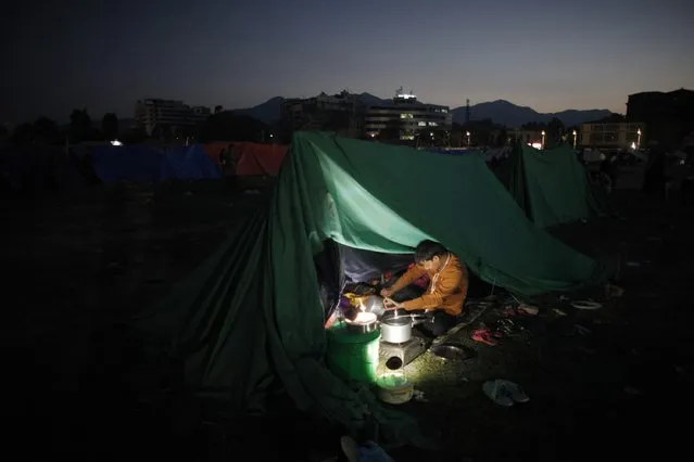 A Nepalese man cooks food inside a tent as people stay on open ground from fears of earthquake tremors in Kathmandu, Nepal, Monday, April 27, 2015. (Photo by Niranjan Shrestha/AP Photo)