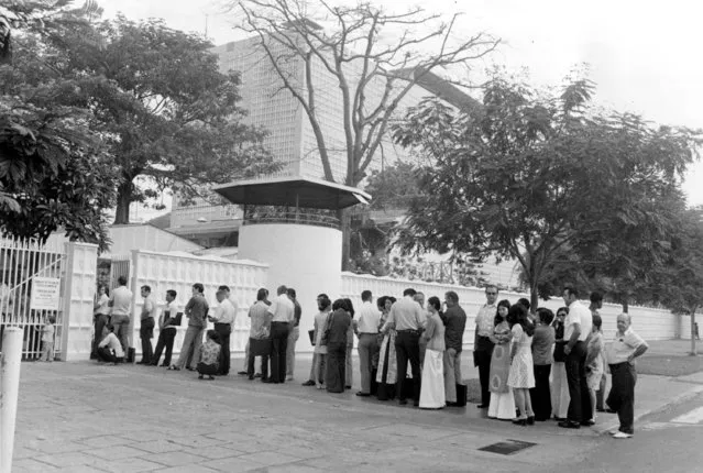 Americans and their South Vietnamese dependents wait in line outside the U.S. consulate to apply for visas in Saigon, Vietnam, Saturday, April 5, 1975. (Photo by AP Photo)