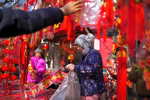 Residents shop for prosperity decorations on the eve of the Chinese Lunar New Year, at a pavement shop in Beijing, Friday, February 9, 2024. (Photo by Andy Wong/AP Photo)