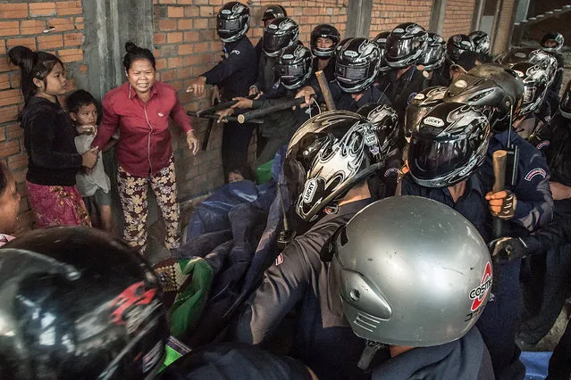 A woman and two children are surrounded by police and municipal security forces during clashes with residents of Borei Keila community on February 14, 2014 in Phnom Penh, Cambodia. A building which has been occupied for the last two days has been raided by the Cambodian Security forces who sought to forcibly evict the residents. (Photo by Omar Havana/Getty Images)