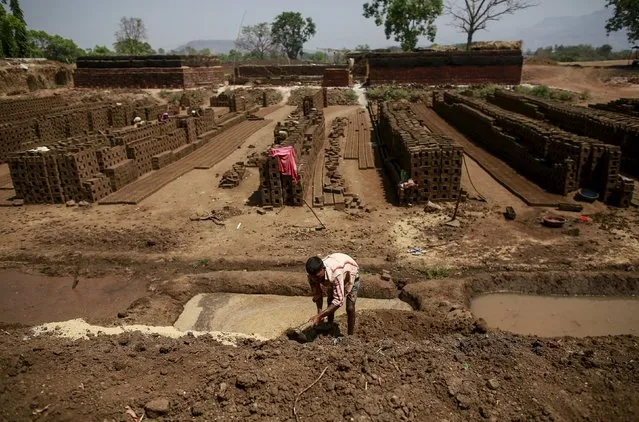 A labourer prepares a mixture for making mud bricks at a kiln in Karjat, India, March 10, 2016. (Photo by Danish Siddiqui/Reuters)