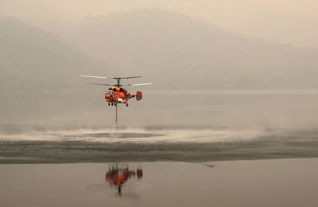 A firefighting helicopter picks up water to combat forest fires amid heavy air pollution at Mae Ngat Somboon Chon Dam in the northern Thai province of Chiang Mai on March 16, 2024. (Photo by Lillian Suwanrumpha/AFP Photo)
