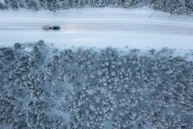 An aerial shot shows a car as it drives on a road through the Arctic wilderness close to Utsjoki, Finland, on November 25, 2021. The sun rises above the horizon and sets again in the far north of Finland for the last time this year, marking the start of the polar night, or “kaamos” which will last until 16 January. The village of Utsjoki, on Finland's northern border with Norway, saw sunrise at 11.34 on Thursday and sunset just 48 minutes later Temperatures in the region, which lies 450 kilometres (280 miles) within the Arctic Circle fell to minus 27 degrees Centigrade (–16.6F). (Photo by Jonathan Nackstrand/AFP Photo)