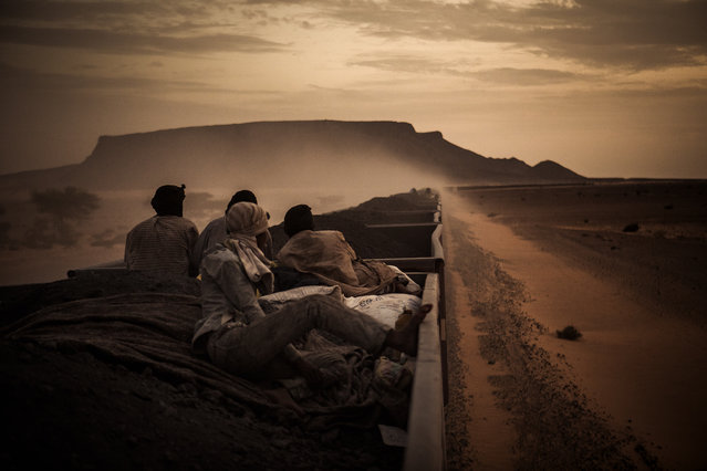 “Young Mohammed Salam – in the foreground – travels regularly on iron ore hoppers through the Mauritanian Sahara, from the open-pit hematite mine center of Zouerat, to the commercial port of Nouadhibou”. (Photo and caption by Rafael Gutierrez Garitano/2014 Sony World Photography Awards)