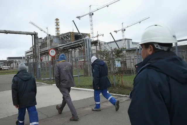 Workers walk past the remains of reactor number four at the former Chernobyl nuclear power plant on September 29, 2015, near Chornobyl, Ukraine. (Photo by Sean Gallup/Getty Images)