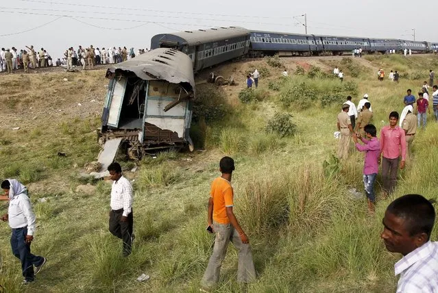 Police and onlookers gather around the damaged coaches of a passenger train after it derailed in Kaushambi district, in the northern state of Uttar Pradesh, India, May 25, 2015. (Photo by Jitendra Prakash/Reuters)