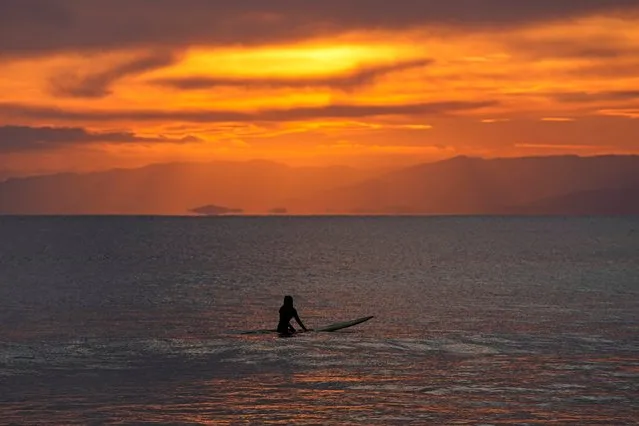 A surfer waits for a wave as the sun sets Friday, December 10, 2021, in Fujisawa, South of Tokyo. (Photo by Kiichiro Sato/AP Photo)