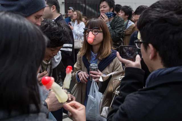 A woman wears a phallic-shaped mask as friends eat phallic-shaped lollipops at the Wakamiya Hachimangu shrine during Kanamara Matsuri (Festival of the Steel Phallus) on April 6, 2014 in Kawasaki, Japan. (Photo by Chris McGrath/Getty Images)