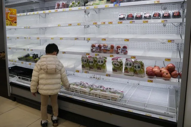 A boy looks at the empty shelves in the vegetable department as residents worry about a shortage of fresh food, at a supermarket in Hong Kong, Tuesday, February 8, 2022. Hong Kong's leader announced on Tuesday the city's toughest social-distancing restrictions yet, including unprecedented limits on private gatherings, as new daily cases surge above 600. (Photo by Kin Cheung/AP Photo)