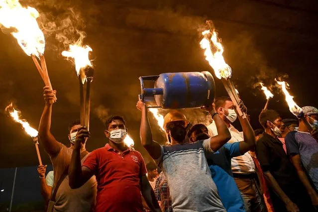 Sri Lanka's main opposition activists hold torches during a demonstration to denounce the shortage of cooking gas, kerosene oil and a few other commodities as the country faces a major foreign exchange crisis, in Colombo on January 5, 2022. (Photo by Ishara S. Kodikara/AFP Photo)