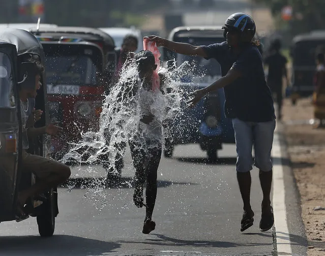 A man pours water on a competitor during a road race as part of traditional festival games to celebrate the Sinhala, the Hindu and Tamil New Year, in Homagama April 20, 2014. Sri Lankans observed their New Year on April 14. (Photo by Dinuka Liyanawatte/Reuters)